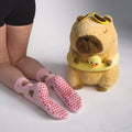 Pink grip socks with brown bear prints worn by a model, shown next to a plush toy in a studio setting.